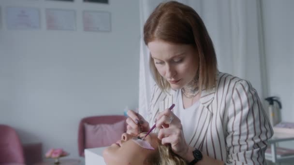 Kobieta Relaksuje Się Łóżku Podczas Gdy Kosmetyczka Używa Metalowej Pęsety — Wideo stockowe