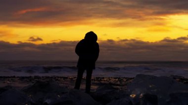 Gün batımında okyanusun kenarında dinlenen bir adam..
