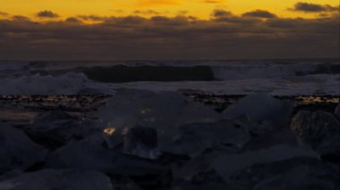 Güçlü dalgalar buzlu bir kıyıya çarpıyor, dramatik ve soğuk bir manzara yaratıyor..