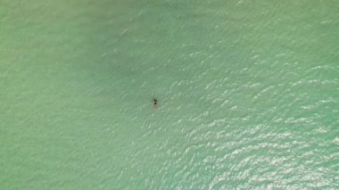 Büyüleyici bir hava perspektifi siyah mayo giymiş bir kadını gerçek bir ada vahası olan Koh Mak 'ın berrak sularında huzur içinde yüzerken yakalıyor.