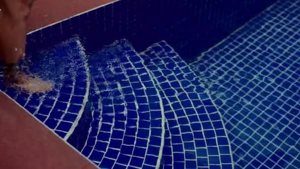 一个女人优雅地走进一个装饰着生机勃勃的蓝色马赛克瓷砖的水池 — 图库视频影像