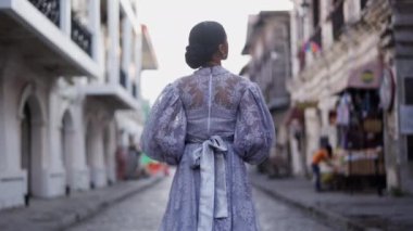 Arkasından yakalanan zarif leylak elbiseli bir bayan şehrin zengin mirasını kucaklayarak Vigan 'ın tarihi caddelerinde sakin bir yürüyüş yapar.