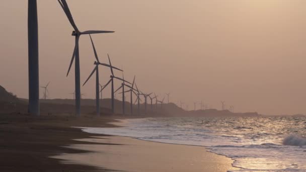 Una Fila Turbine Eoliche Una Spiaggia Sabbiosa Che Schianta Dolcemente — Video Stock