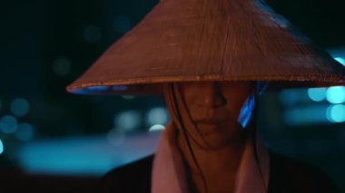 Konik şapka takan bir kadın bakışlarını yukarı kaldırır. Hareketleri kasıtlı ve ölçülü olur.