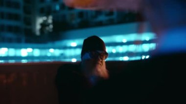 Güneş gözlüklü sakallı bir adam bir dizi Kung Fu tekniğini incelikle uygular. Hareketleri güç ve akıcılığı harmanlar.