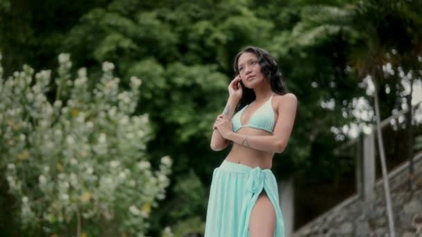 Elegancka Kobieta Pozuje Pośród Tętniącego Życiem Ogrodu Zakładając Bikini Akwamarynu — Wideo stockowe