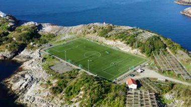 Bir futbol sahasının üzerinde, nefes kesici bir deniz manzarası tarafından kucaklanan bir dron belirir.