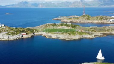 Uzak bir dağ sırası tarafından çerçevelenmiş bir kıyı futbol sahasının havadan çekilmiş görüntüsü.