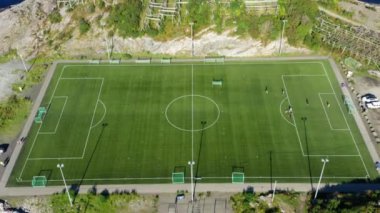 Yarı sahada oynanan bir futbol maçının havadan çekimi kıyı stadyumunda sallanırken okyanus nefes kesici bir zemin oluşturur.