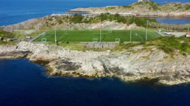 Ufukta dağlar olan bir adadaki açık hava futbol stadyumunun havadan çekilmiş görüntüsü.