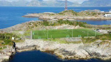 Ufuktaki uzak dağlar tarafından çerçevelenmiş, ada merkezli açık bir futbol stadyumu.