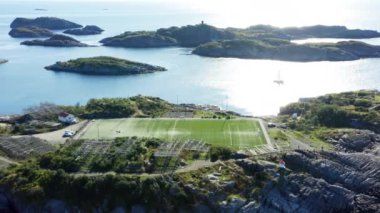 Gök mavisi deniz tarafından çerçevelenmiş bir futbol sahasının havadan çekilmiş görüntüsü ve gündüz adaların dağılması.