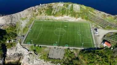 Açık denizin uçsuz bucaksız genişliğiyle çevrili bir futbol sahasının havadan çekilmiş görüntüsü.