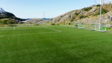 Gündüz vakti bir kıyı futbol sahasını kale ağlarıyla gösteren geri çekilen bir çekim
