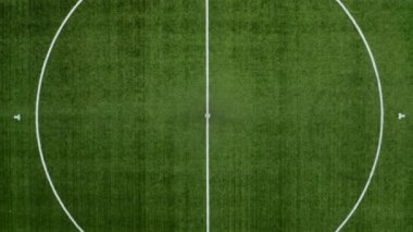 Kamera zarif bir şekilde futbol sahasının ortasındaki çemberden çekilerek, alanın ve çevrenin geniş açısını yakalıyor.