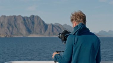 Bir film yapımcısının, dağların ve engin mavi denizin ortasında bir feribot yolculuğunu kaydedişinin arka plan çekimi.