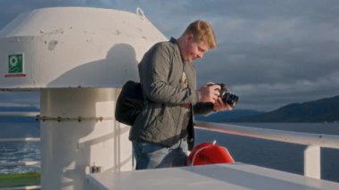 Gri ceketli bir sinemacı, denizin ilham verici güzelliğini yakalıyor ve feribot yolculuğu sırasında yüksek dağları tırmanıyor.