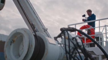 Alçak açılı görüntü gün batımında feribot yolculuğunda bir film yapımcısını kaydediyor.