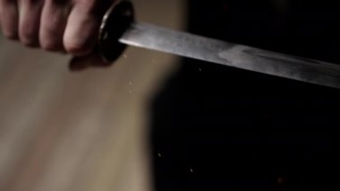 Japon kılıcını nazikçe tutan ve kıvılcımlar saçan bir elin yakın çekimi.