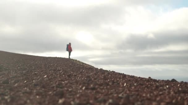 ラウダスカルクレーターの赤い火山の土の上に立っている男の傾斜したショットは 曇った日に広大な景色を眺めながら — ストック動画