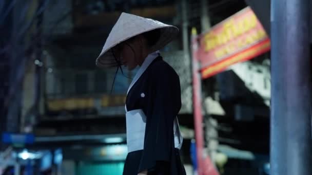 一个戴着草帽和传统和服的女人 晚上走在繁华的城市街道上 — 图库视频影像
