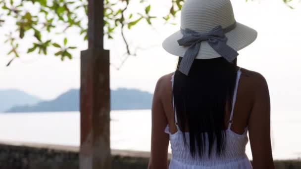 Μια Γυναίκα Φορώντας Ένα Καπέλο Ηλίου Και Λευκό Φόρεμα Ατενίζει — Αρχείο Βίντεο