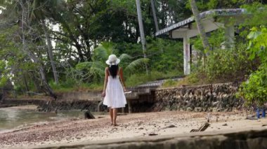 Tayland 'da, Ko Chang' de terk edilmiş bir villanın yakınındaki engebeli sahili keşfeden bir bayanın geniş açılı bir görüntüsü.