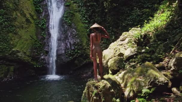 Una Mujer Bikini Para Una Gran Roca Ajustando Sombrero Paja — Vídeos de Stock