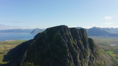 Dağ zirvesi güneş ışığıyla yıkanmış, gündüz vakti gökyüzüne karşı doğanın engebeli güzelliğini sergiliyor.