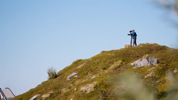 青空に向かって丘の上から映像を撮影するビジョナリー映画監督 — ストック動画
