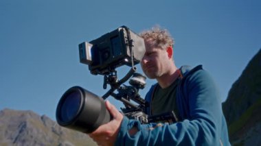Mavi kapüşonlu bir film yapımcısı nefes kesici bir arka plan ve engin mavi bir gökyüzü arasında kayıt yapıyor.