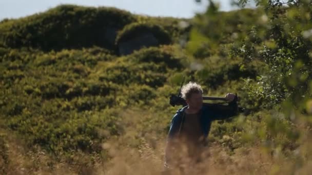 Filmař Nesoucí Stativ Rameni Když Projíždí Travnatým Terénem Slunečného Dne — Stock video