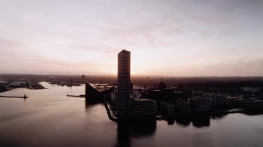 Danimarka 'nın Aarhus limanındaki binalara gün batımının arka planına doğru bir dron yavaşça yaklaşıyor.