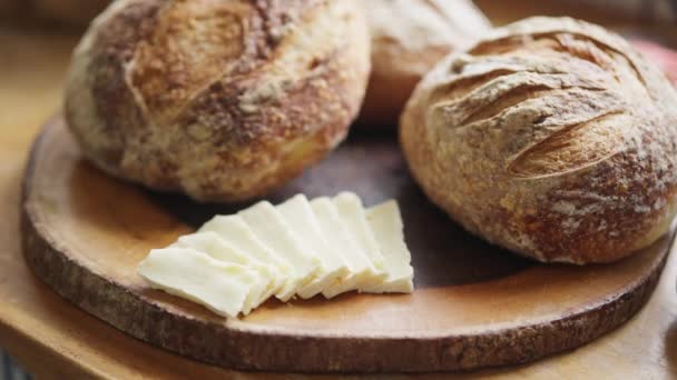 Zbliżenie Ujęcie Bochenków Chleba Rzemieślniczego Kawałek Masła Drewnianej Desce Krojenia — Wideo stockowe