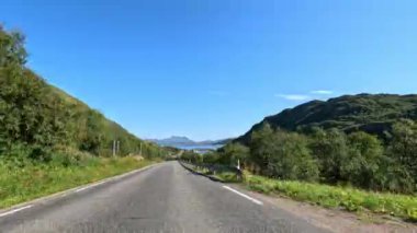 Gün ışığında Lofoten 'ın kıyı yolu boyunca hayranlık uyandıran dağ manzaralarını gösteren hızlandırılmış bir video.