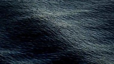 Yumuşak dalgalar, derin mavi bir okyanusun yüzeyinde ritmik olarak yuvarlanıyor.