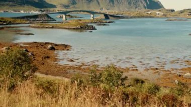 Gündüz vakti Lofoten 'ın görkemli dağlarının dramatik zeminine karşı kurulmuş iki köprüyü gösteren eğik bir çekim.