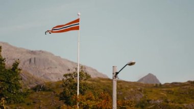 Göz kamaştırıcı Norveç bayrağı, görkemli dağ manzaralarının arka planında sergileniyor.