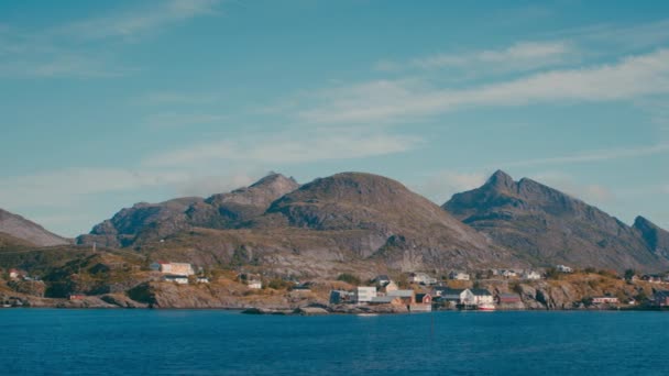 左から右に移動するパノラマショット 山の背景に海に囲まれたソルヴェーゲンの魅力的な家をフィーチャー — ストック動画