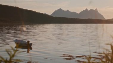 Gün batımında gölde hareketsiz bir tekne.