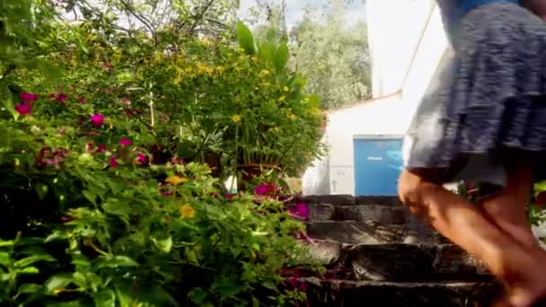 Seorang Gadis Anggun Naik Tangga Taman Dikelilingi Oleh Bunga Mekar — Stok Video