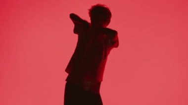 Genç bir dansçının silueti, serbest stil hip-hop dansı yapar. Kırmızı arka planda ağır çekimde dans eder.