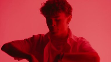 Parlak kırmızı bir arka planda elleri ile dans eden genç bir adamın yakın çekimi.