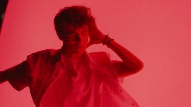 Parlak kırmızı bir arka plana karşı ağır çekimde hip-hop dansı yapan bir dansçı.