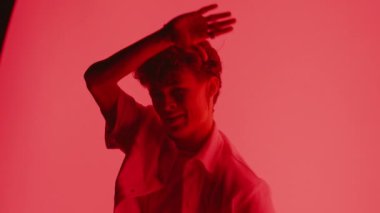 Bir adam kırmızı arka planda modern bir dans gösterisi yaptıktan sonra kameraya bakar ve yavaşça arkasını döner.