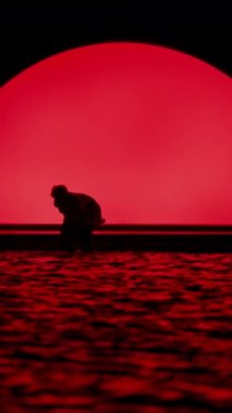 Sahne kenarında, karanlıkta dans eden bir adamın, parlak kırmızı arka planlı, yavaş çekim görüntüsü.