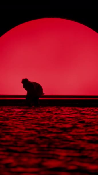 一个男人在海滨舞台附近的黑暗中跳舞的慢镜头 背景是鲜红的 — 图库视频影像