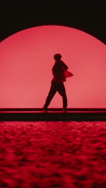 남자의 실루엣 어두운 무대에서 빨간색 달무리 배경에 — 비디오
