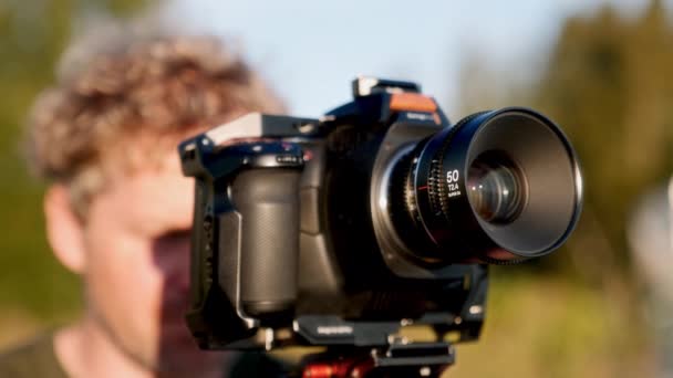熟練した映画製作者は 太陽の輝かしい光線の下でプロのカメラを巧みに使用します — ストック動画