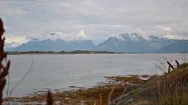 Geniş açılı bir çekim, Norveç 'teki Skutvik' in sakin sularına kısmen bulutlarla kaplı bir sıradağları yakalıyor.